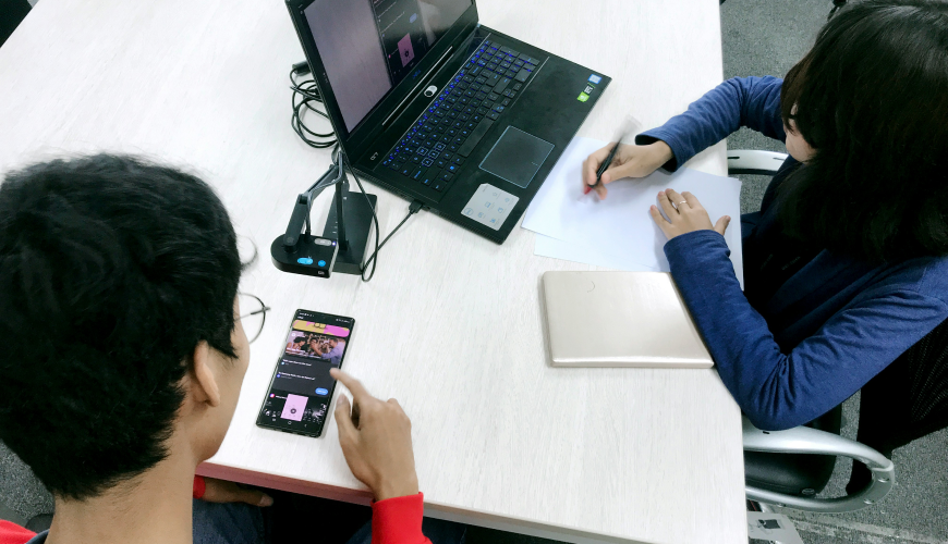 A usability testing session with users interacting with a mobile app while being observed, showcasing the UX principle of validating usability and performance through real-world testing.